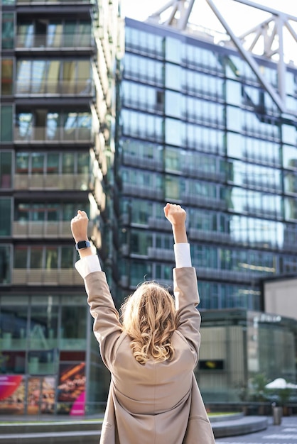 Бесплатное фото Вид сзади на корпоративную женщину-адвоката, празднующую поднятие рук вверх и торжество достижения цели или успеха