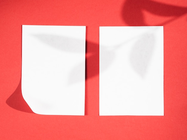 Бесплатное фото Красный фон с тенью ветки листа на двух белых одеялах