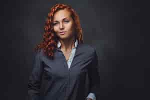 Free photo redhead female supervisor dressed in an elegant suit over grey background.