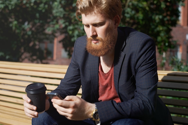 Free photo sad beard man uses phone to find new job