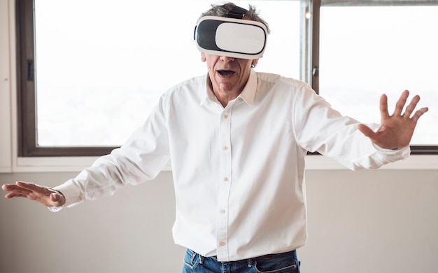 Senior man in white shirt using a virtual reality headset in the room