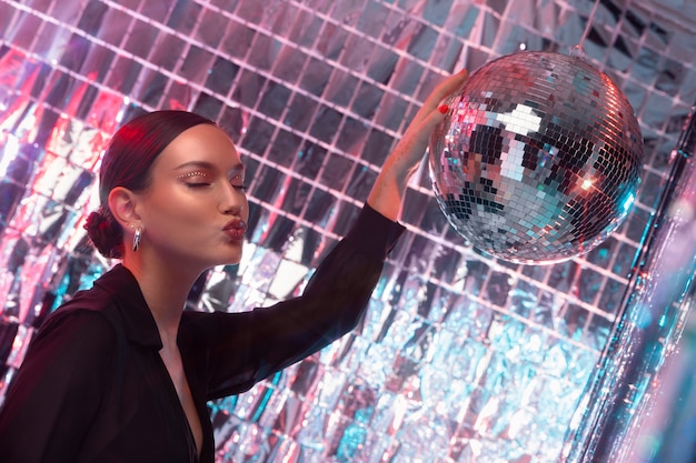 Бесплатное фото Вид сбоку девушка позирует с диско-шаром