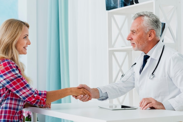 Free photo side view doctor shaking patient hand