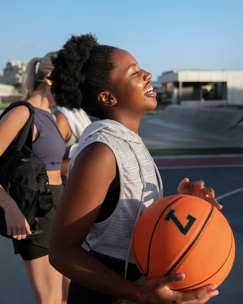 Foto gratuita amici femminili di vista laterale che giocano a basket