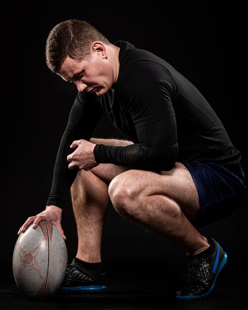 Side view of male rugby player holding ball with one hand