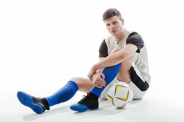 Бесплатное фото Футболист с мячом, сидя на полу