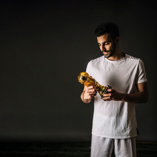 Бесплатное фото Футболист с трофеем фифа