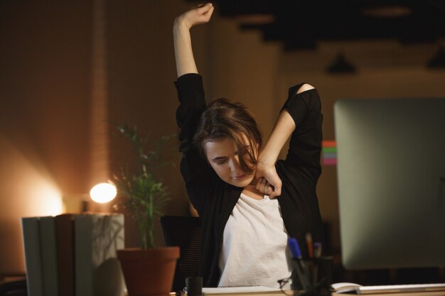 Sleepy woman stretching in office