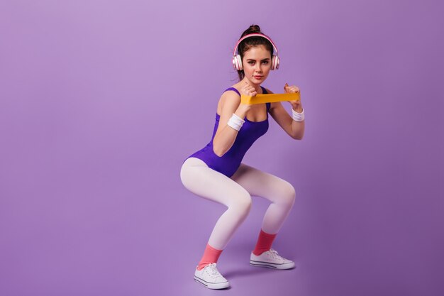 Бесплатное фото Стройная женщина занимается спортом на фиолетовой стене
