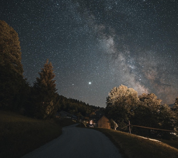 Бесплатное фото Гладкая дорога, проходящая через живописную сельскую местность под ночным звездным небом с млечным путем