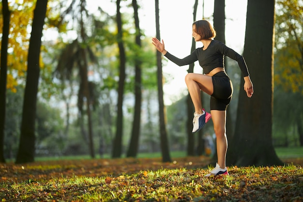 Бесплатное фото Улыбающаяся активная женщина делает фитнес-упражнения в парке