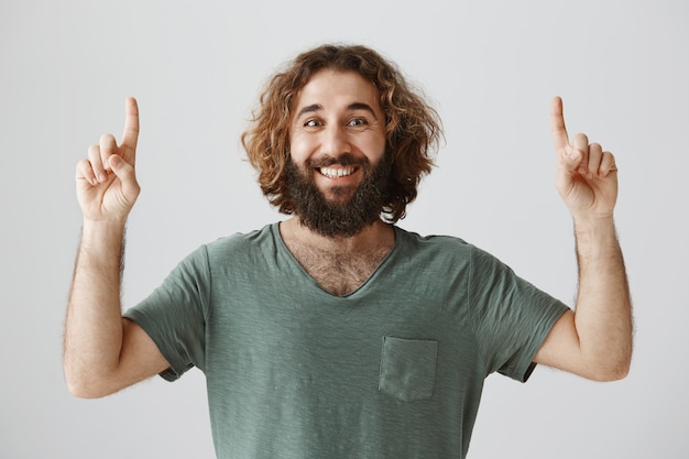 Бесплатное фото Улыбающийся бородатый мужчина с ближнего востока, указывая пальцем вверх