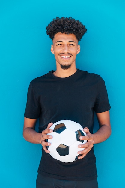 Улыбающийся этнический парень стоял с футболом