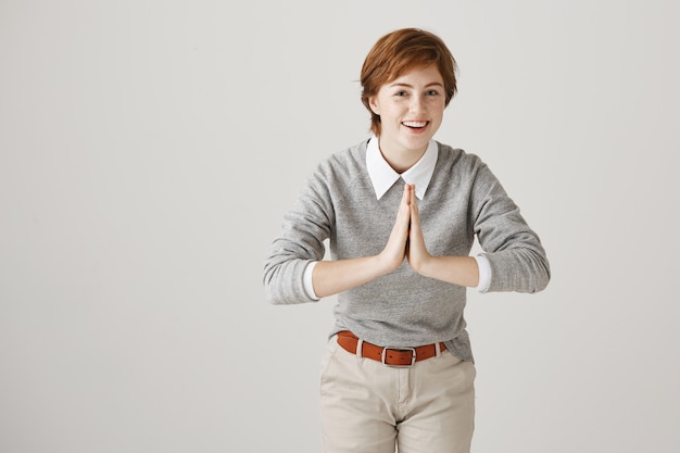 Free photo smiling redhead girl with short haircut posing against the white wall
