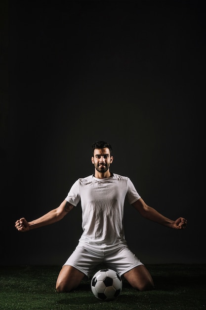 Бесплатное фото Улыбающийся спортсмен, сидящий рядом с мячом