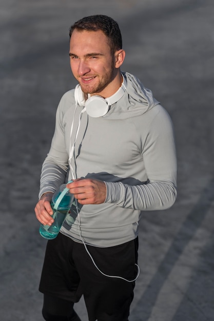 Бесплатное фото Улыбающийся спортивный человек, держащий бутылку воды