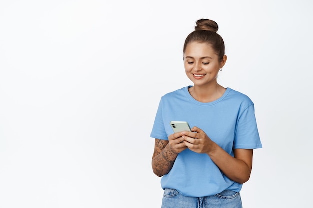 Бесплатное фото Улыбающаяся женщина с помощью мобильного телефона, глядя на экран. концепция заказа такси, приложения и технологии