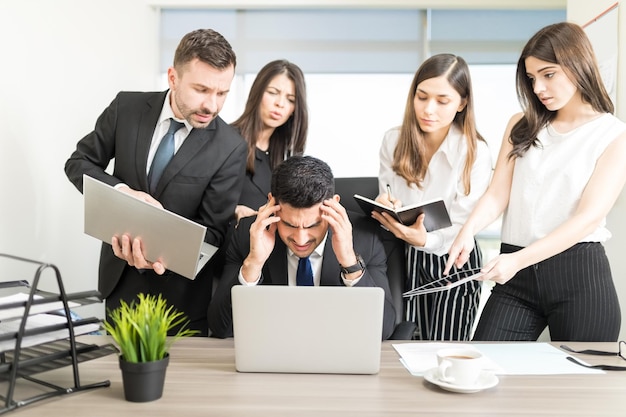 Free photo stressed businessman unable to cope with too much work assigned by colleagues in office