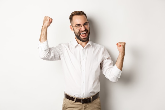 Бесплатное фото Успешный бизнесмен радуется, поднимает руки и празднует победу, что-то выигрывает