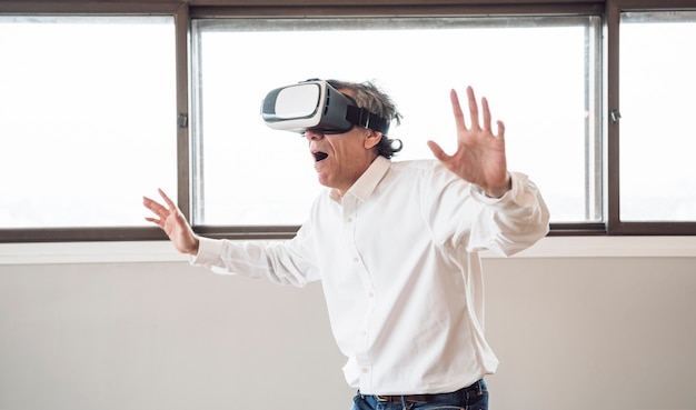 Free photo surprised senior man using a virtual reality headset in the room