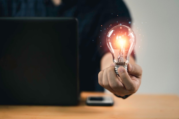 Photo gratuite main d'homme d'affaires tenant une ampoule avec une lumière rougeoyante pour une pensée intelligente créative pour l'inspiration et l'innovation avec le concept de réseau