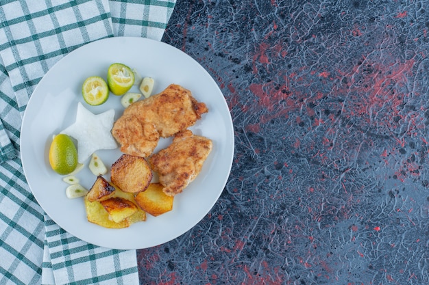 Photo gratuite une assiette blanche de viande de poulet avec pommes de terre frites.