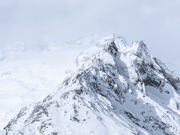 Photo gratuite beau plan large de montagnes couvertes de neige sous un ciel brumeux