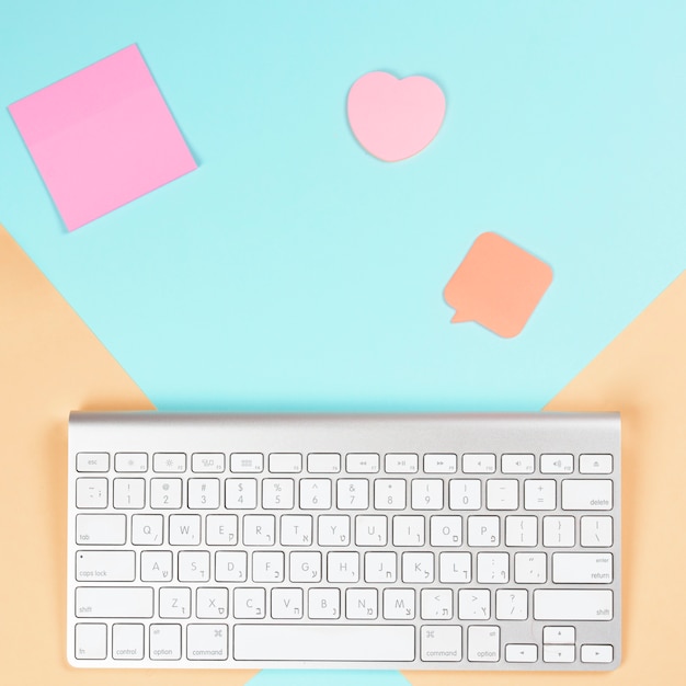 Photo gratuite bloc-notes adhésif; forme de coeur et bulle avec clavier blanc sans fil sur double fond
