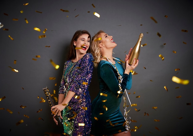 Photo gratuite femmes au champagne sous la douche de confettis