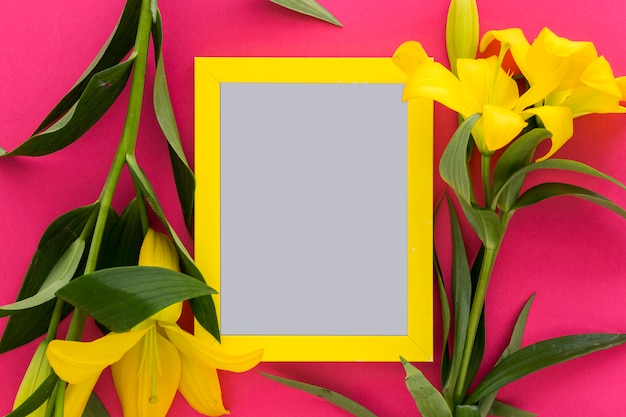 Photo gratuite fleurs de lis jaune et cadre d'image vide au-dessus du rose; contexte