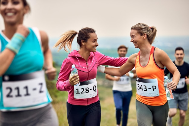 Photo gratuite heureuses femmes athlétiques se soutenant lors d'un marathon dans la nature