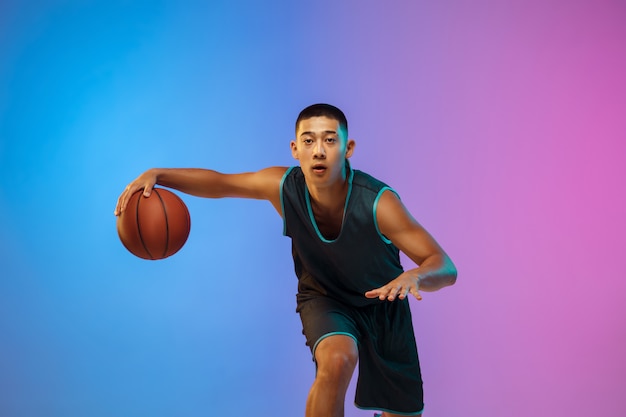 Photo gratuite jeune basketteur en mouvement sur fond de studio dégradé en néon