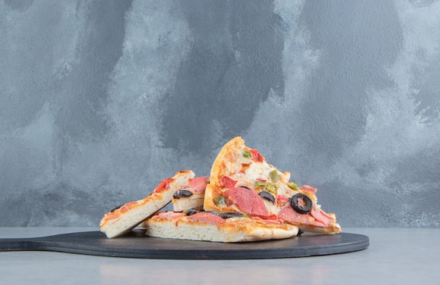 Photo gratuite un petit tas de tranches de pizza sur un tableau noir sur marbre