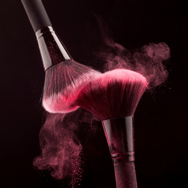 Photo gratuite pinceaux de maquillage avec poudre rose tourbillonnante