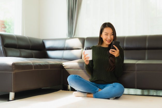 Photo gratuite portrait belle jeune femme asiatique utiliser un téléphone mobile intelligent avec une tasse de café