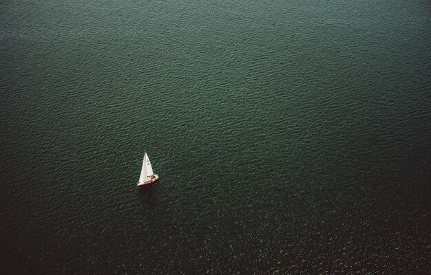 Photo gratuite vue aérienne d'un petit bateau naviguant dans le large et magnifique océan