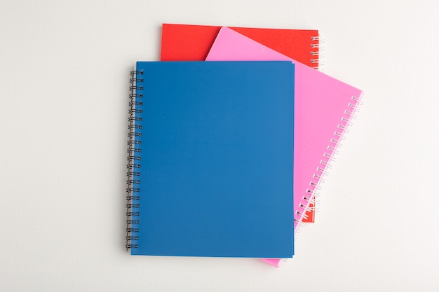 Photo gratuite vue de dessus différents cahiers colorés sur la surface blanche