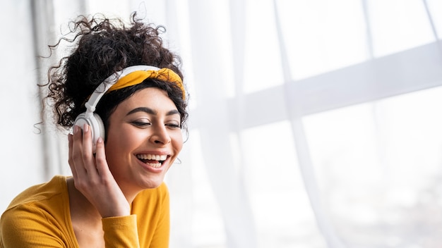 Photo gratuite vue de face d'une femme heureuse en riant et en écoutant de la musique sur des écouteurs avec espace de copie