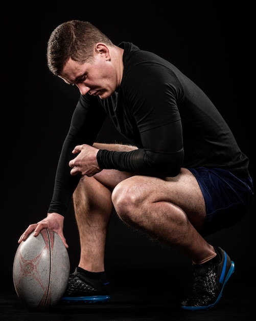 Vue latérale du joueur de rugby masculin tenant le ballon avec une main