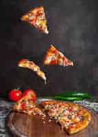Photo gratuite vue latérale pizza au poivre et tomate et tranches de pizza dans une batterie de cuisine à bord