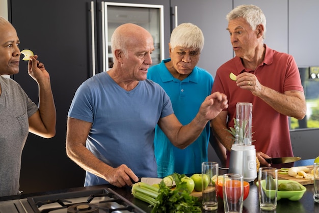 Photo des amis seniors heureux et diversifiés discutent des ingrédients pour préparer des smoothies sains dans la cuisine.