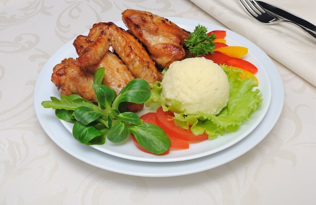 Photo ailes de poulet au four dans une marinade au miel et au soja avec ail et pommes de terre et légumes