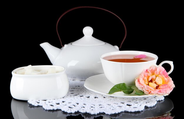 Photo bouilloire et tasse de thé de thé rose sur fond noir de serviette