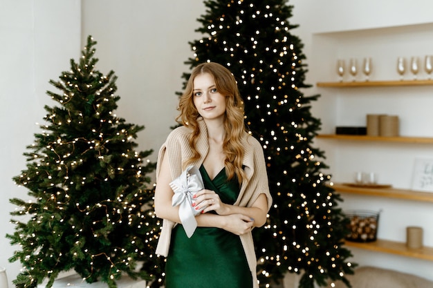 belle femme sourit dans le contexte d'un arbre de Noël à la maison