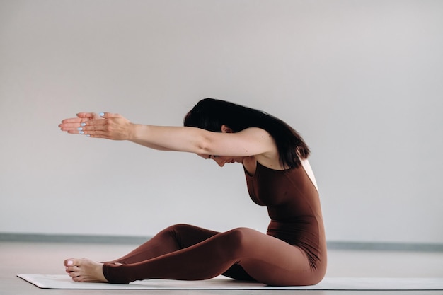 Photo une femme en costume marron fait du yoga dans une salle de fitness