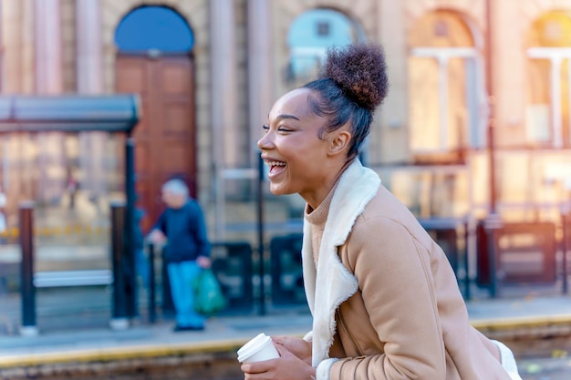 Photo une femme brune bouclée souriante dans un chandail attendant un tram