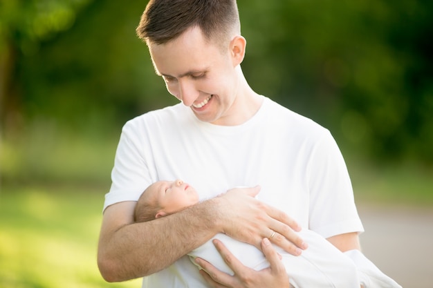 Photo homme debout avec un bébé dans ses bras dans le parc
