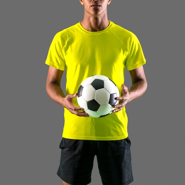 Photo homme joueur de football avec un jeu de peau sombre attraper une balle avec ses mains sur fond sombre