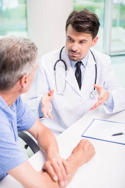 Homme médecin parle sérieusement avec le patient à la clinique.