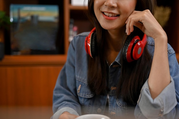 Image recadrée Une belle femme asiatique en veste en jean et casque sans fil